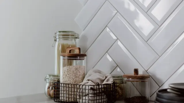 A measuring scoop of supplement powder resting beside a jar on a kitchen counter